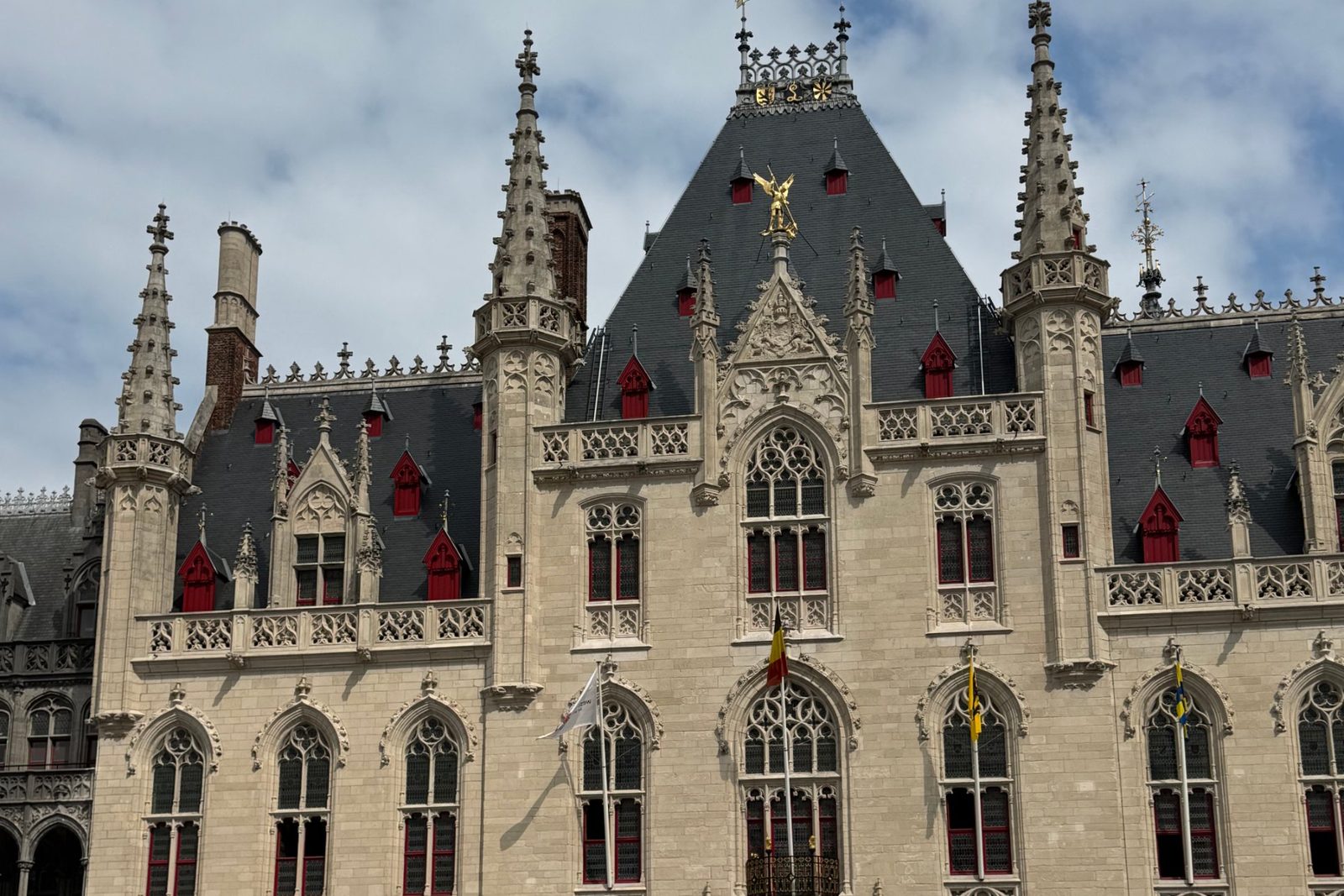 The Gothic Provincial Court on the Markt in Bruges under a cloudy blue sky