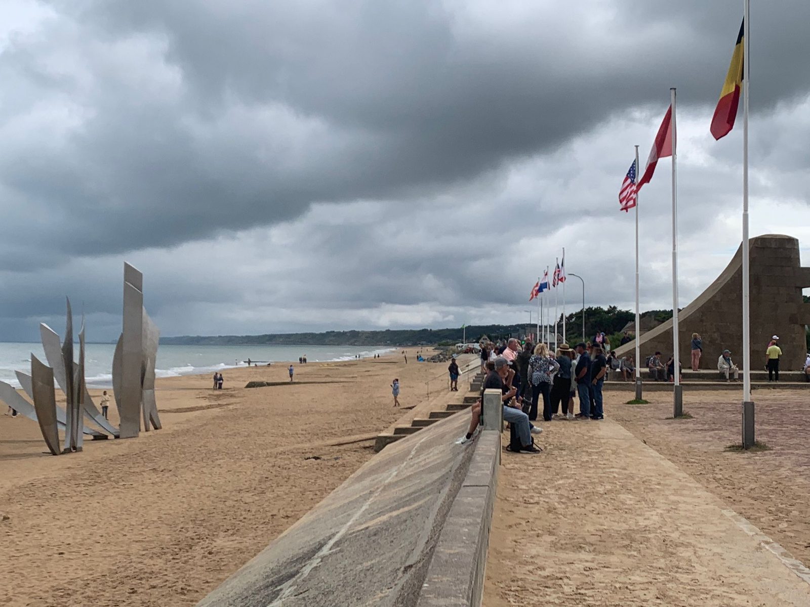 Omaha Beach at low tide with the Les Braves sculpture and a row of flags
