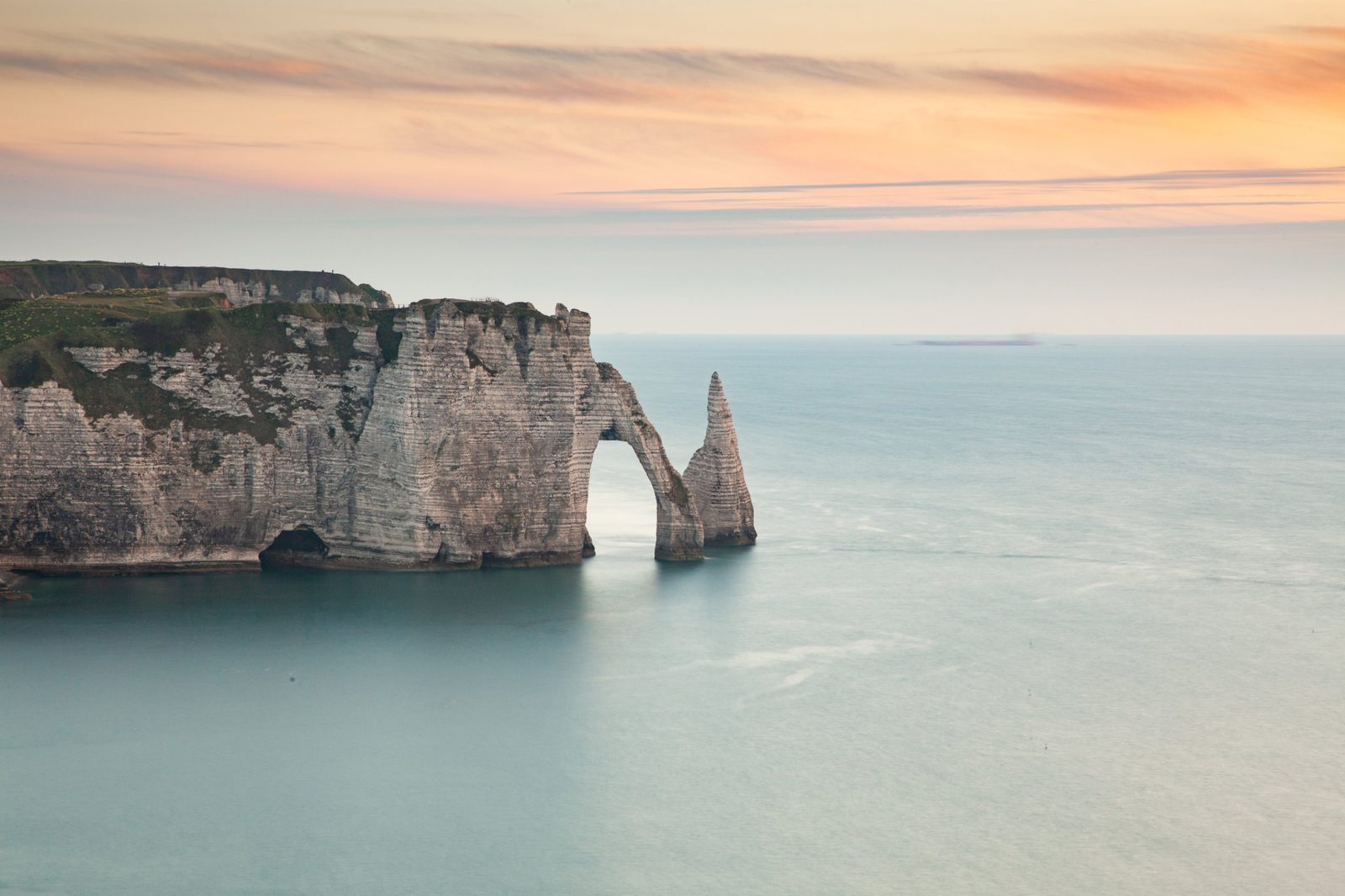 The natural arch and white cliffs of Etretat at sunset
