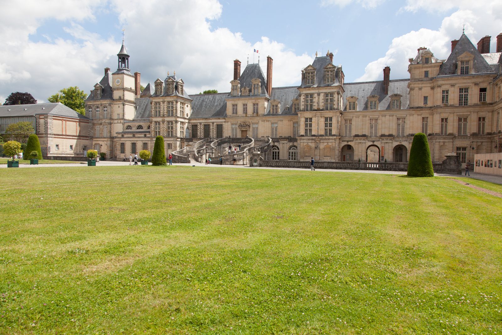 The horseshoe staircase and courtyard facade of Chateau de Fontainebleau on a sunny day