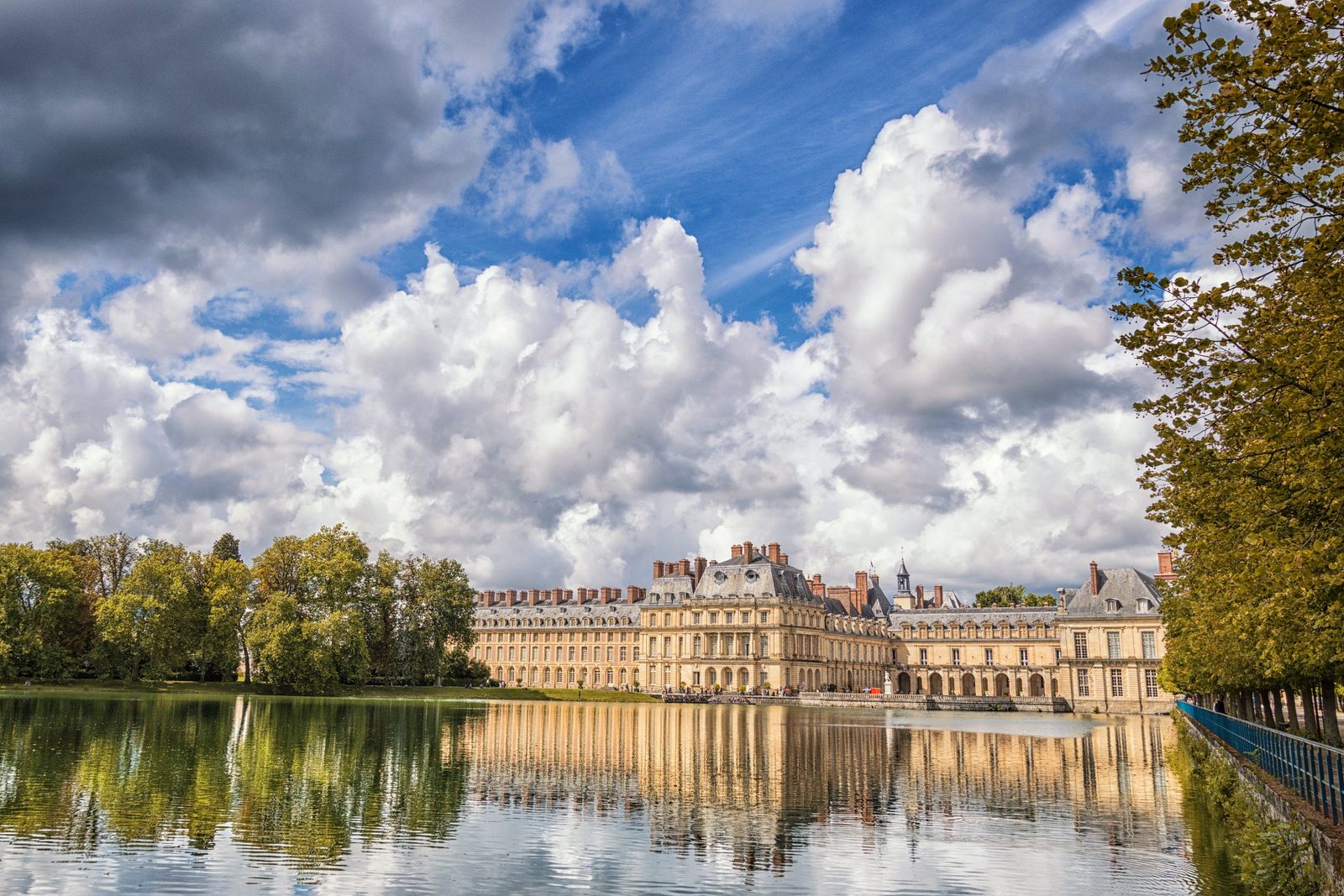 Chateau de Fontainebleau reflected in the Carp Pond under a sky of white clouds