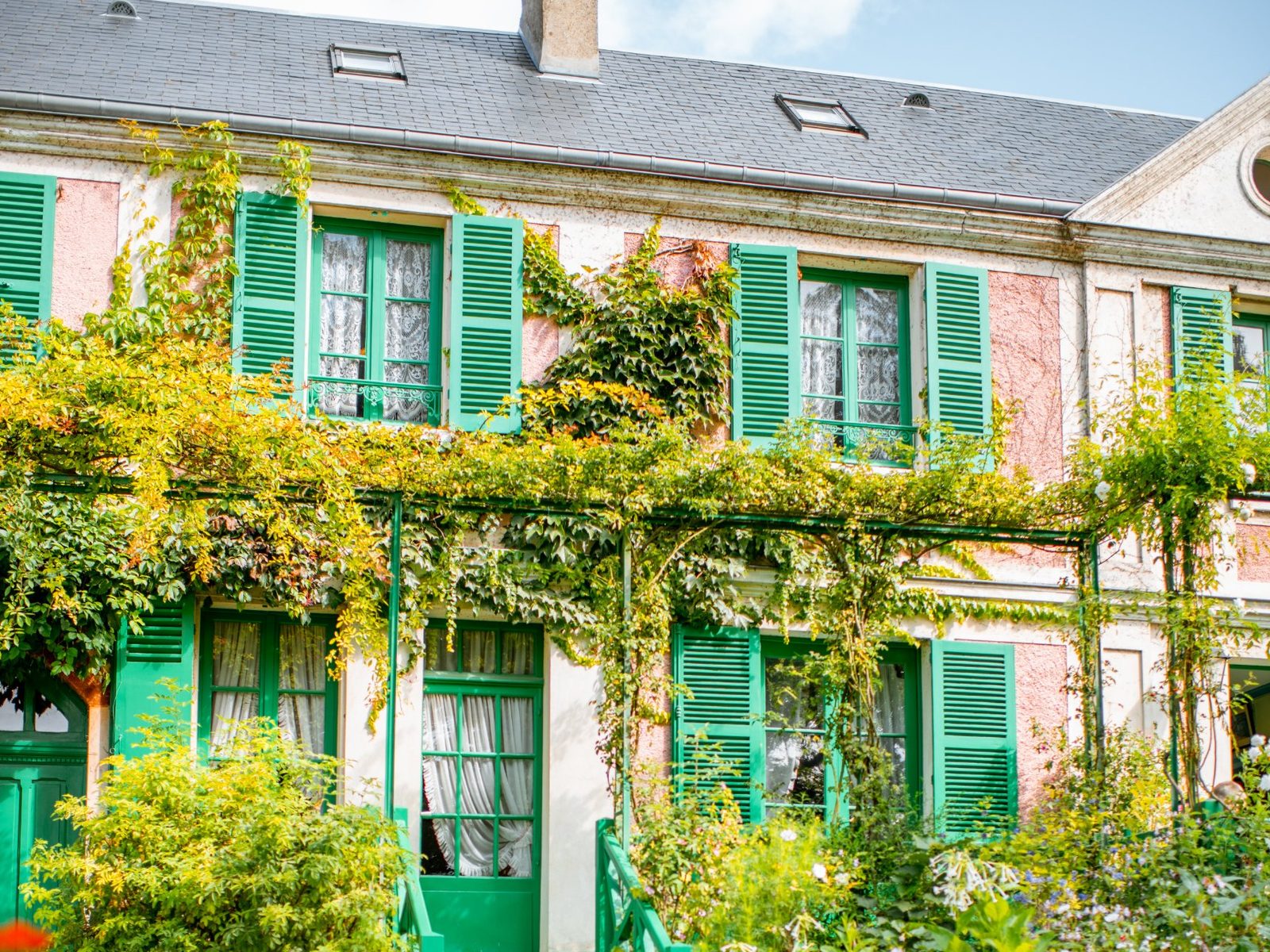 The pink house with green shutters and red geraniums at Giverny