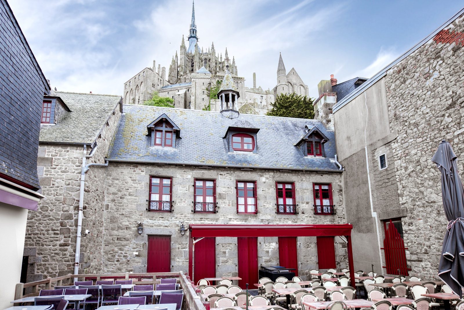 Stone houses with red windows in Mont-Saint-Michel village below the abbey