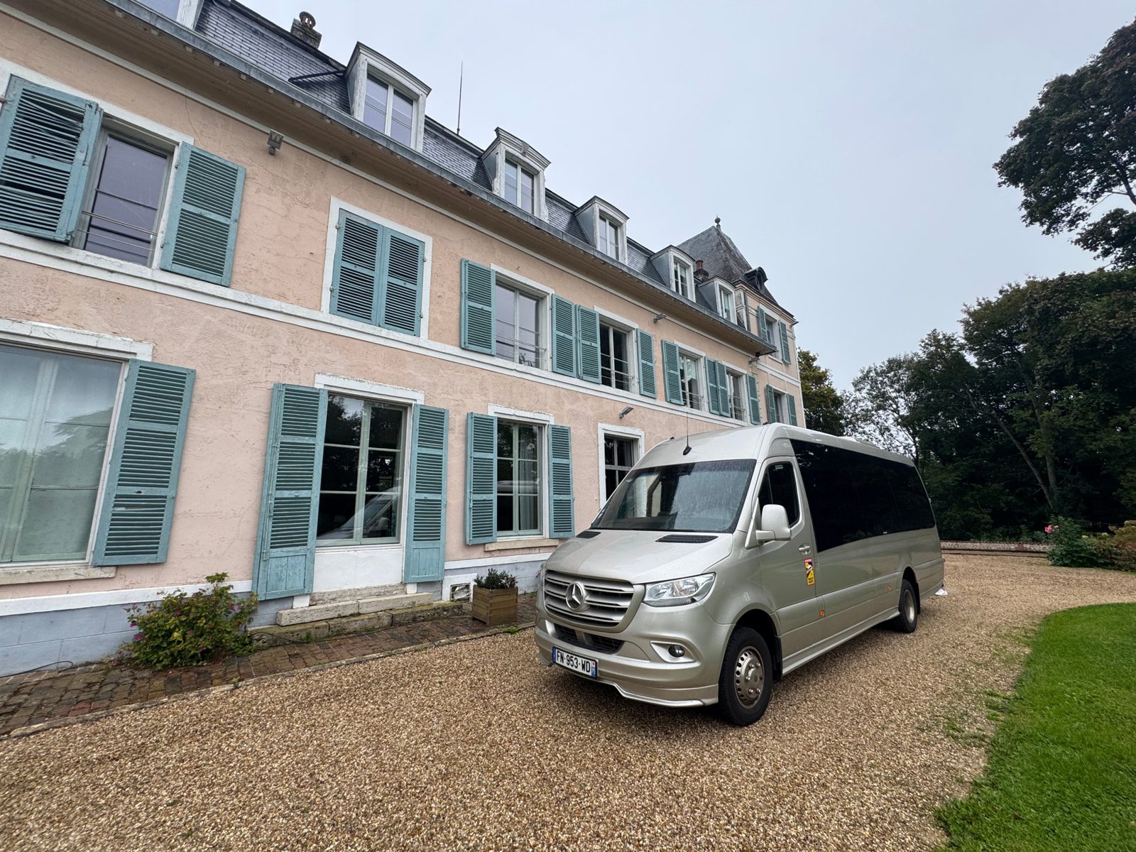 Silver Mercedes Sprinter minibus parked in front of a country house in Normandy