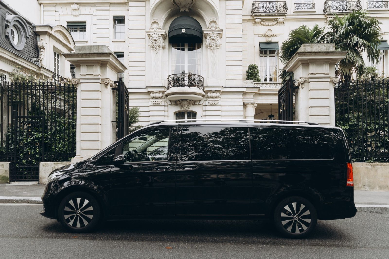 Side view of a black Mercedes V-Class in front of a Paris mansion