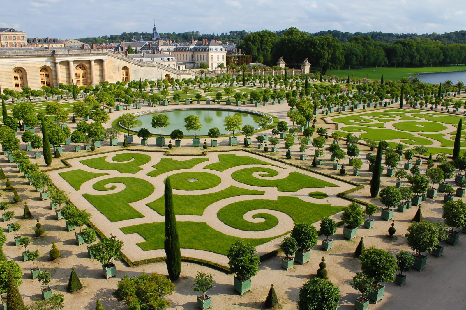 The Orangerie garden at Versailles with trimmed lawns, orange trees in green boxes and a round pond
